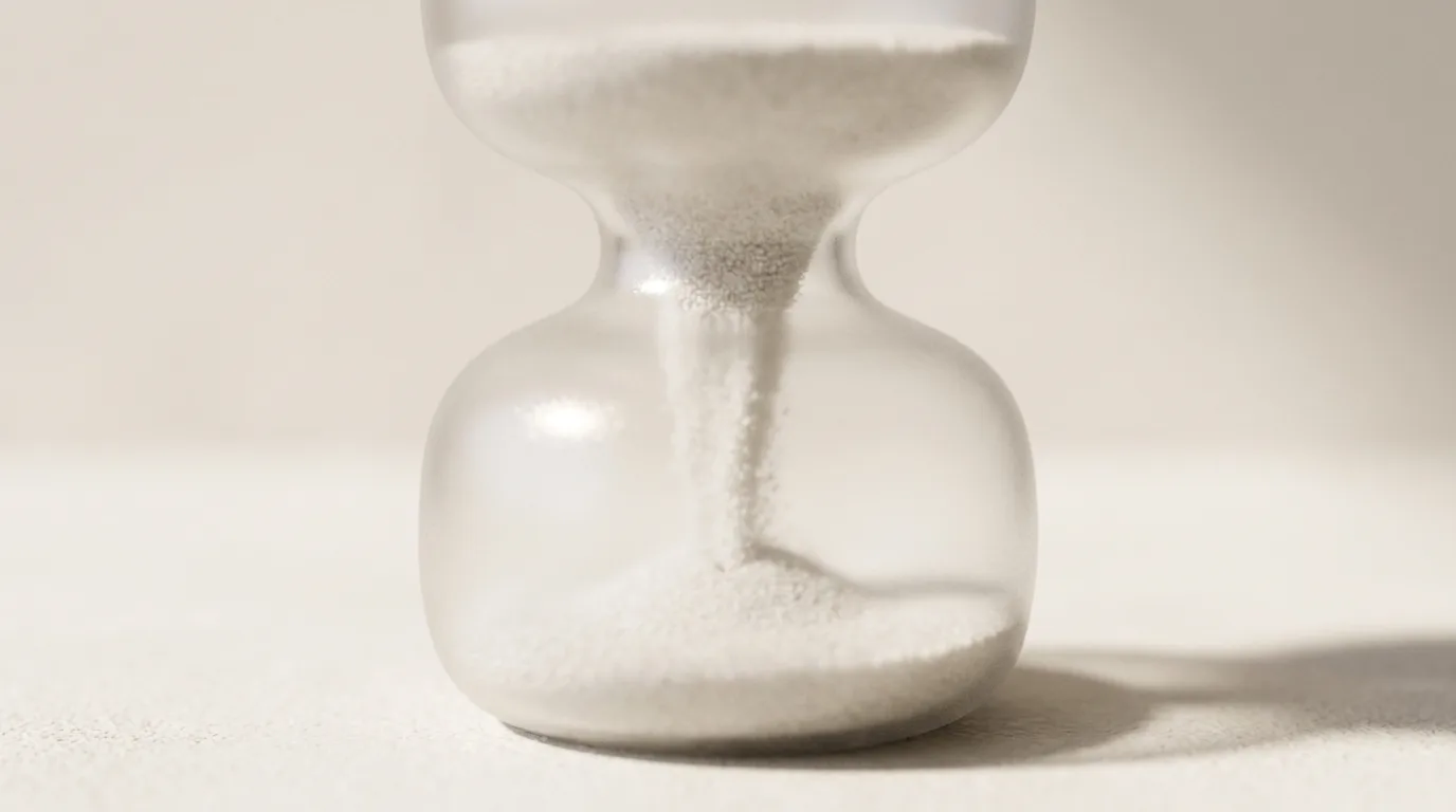 Sablier de verre dépoli au col très large, le sable blanc coule d'un seul trait